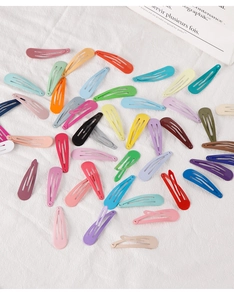 Macro detail of various colorful candy-colored teardrop snap hair clips on woven texture
