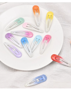 Close-up of gradient glitter snap hair clips in a white porcelain dish with cotton cloth