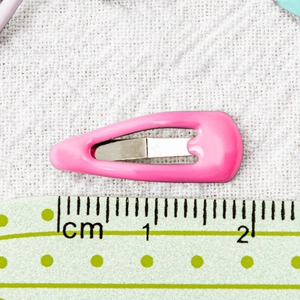 Bright pink 2cm mini pet hair clip with metal drop glue finish on white fabric background