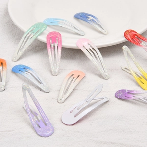 Colorful gradient metal BB clips with glitter finish displayed on a ceramic plate