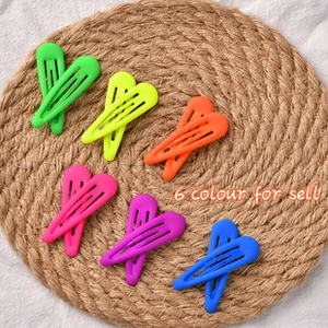 Set of 12 matte heart-shaped BB hair clips in 6 fluorescent colors on a woven mat