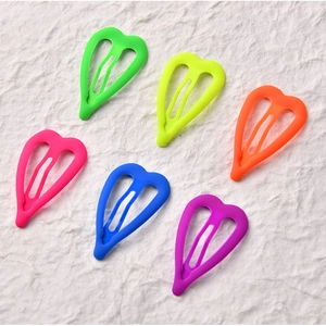 Detail of neon matte heart-shaped metal hair clips in six vibrant dopamine colors