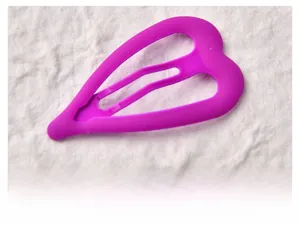 Close-up of heart-shaped bright purple matte BB hair clip on textured fabric background