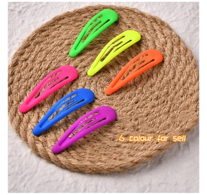Detailed view of six colorful matte snap hair clips in neon shades on a woven mat
