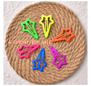 Macro detail of six colorful star-shaped matte hair clips on a woven straw mat