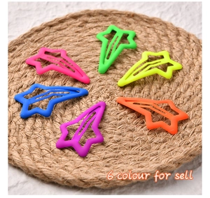 Close-up of six neon star hair clips with matte finish on a woven mat display