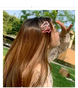 Detail of pink star-shaped metal hair clips worn by a model in a natural outdoor setting