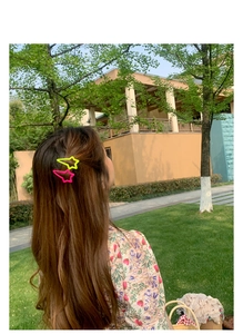 Star-shaped hair clips in neon yellow and pink colors shown on hair outdoors