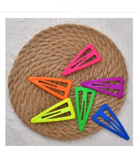 Vue détaillée de six barrettes à cheveux triangulaires mates aux tons fluorescents sur un tapis