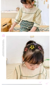 Close-up of colorful matte star-shaped hair clips worn by a young girl in a cozy home setting