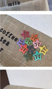 Close-up of colorful matte star-shaped hair clips in 11 macaron colors on burlap