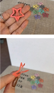 Detail of candy-colored star-shaped metal hair clips showing opening mechanism and scale