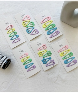 Détail de pinces à cheveux macaron colorées en formes d'étoile et de cœur sur carte