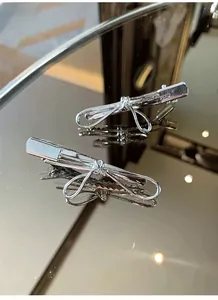 Close-up of dual silver bow hair clips with polished metal finish and duckbill clip detail