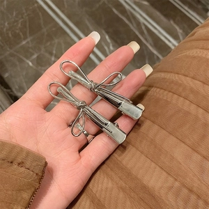 Detailed macro view of two silver metal bow hair clips with a woven textured finish