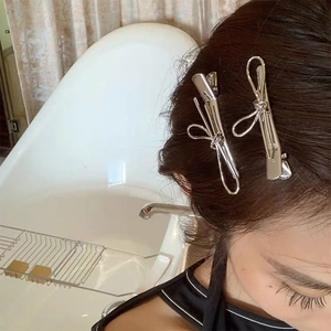 Close-up of a model wearing minimalist silver bow-shaped hair clips in high-shine finish