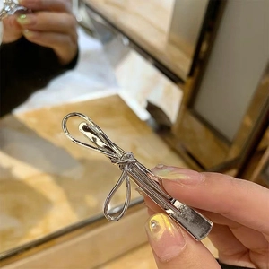 Detail of silver metallic bow hair clip with polished finish and duckbill clasp