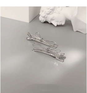 Detailed view of silver bow-shaped hair clips with secure non-slip duckbill grip