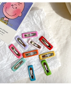 Close-up of colorful candy-colored square BB hair clips arranged on white artistic paper