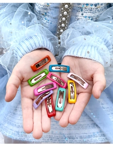 Close-up of vibrant candy-colored metal snap hair clips for kids in various bright shades