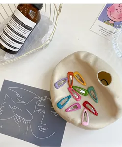 Detailed view of ten colorful drip oil snap clips on a ceramic tray for children