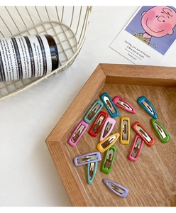 Detail view of colorful candy-colored rectangle snap hair clips in a wooden tray