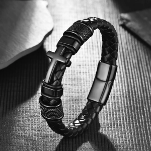 Detail of men's braided leather bracelet with black cross and textured metal beads