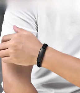 Close-up of men's braided black leather bracelet with matte black metal plate on wrist