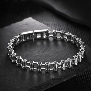 Detailopname van een metalen fietsketting armband op een donkere stenen achtergrond
