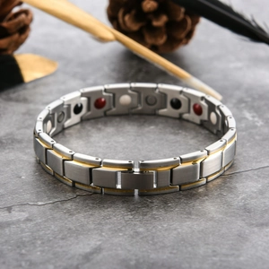 Detail view of two-tone magnetic therapy bracelet with inset health stones on dark stone background