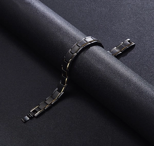 Detail of matte black and gold link bracelet with magnetic clasp on a textured stand