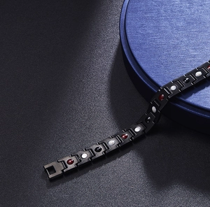 Detail of black magnetic titanium steel bracelet with red, white and black round stone inlays