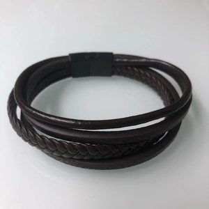 Detail of multi-layer brown leather bracelet with braided strands and black magnetic clasp