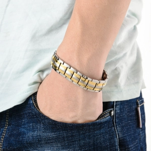 Detail of silver and gold stainless steel magnetic bracelet worn with casual denim wear