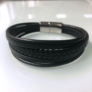 Detail view of multi-layer black braided leather bracelet with silver magnetic buckle