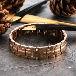 Close-up of rose gold magnetic therapy bracelet with inset health stones on marble
