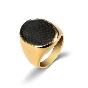 Detalle de un anillo de sello dorado para hombre con inserción de fibra de carbono negra