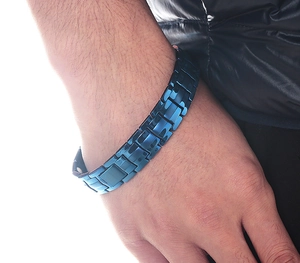 Close-up of blue stainless steel magnetic bracelet with folding clasp on a male wrist