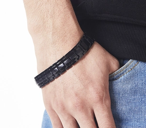 Close-up of men's black stainless steel linked magnetic bracelet on wrist with a casual look
