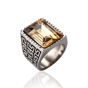 Macro shot of silver stainless steel ring featuring amber emerald-cut stone and Greek key pattern