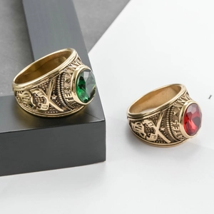 Detail of vintage gold military rings with red and green faceted stones and emblems