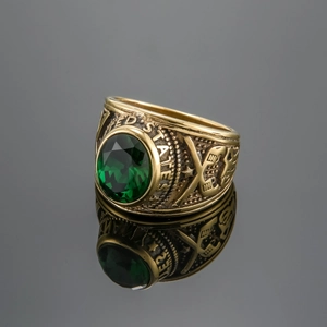 Detail of gold military ring featuring a green faceted stone and engraved United States text