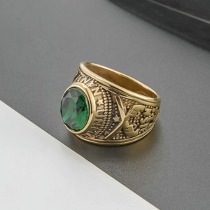 Detailed macro of gold-plated college ring with oval green gemstone and side engravings