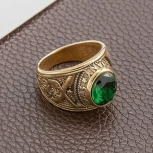 Detail view of gold military ring with emerald green stone and engraved star patterns