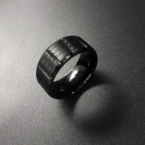 Macro detail of men's wide black stainless steel ring with horizontal industrial grooves