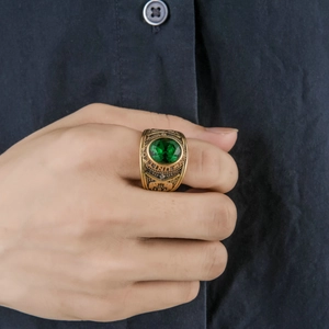 Detailed view of a men's vintage gold ring with green gemstone on hand