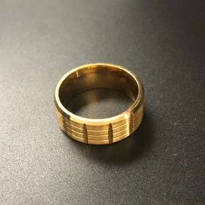 Detail showing the brushed gold finish and vertical grooves on the stainless steel ring