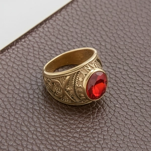 Macro detail of gold stainless steel military ring with red stone and navy eagle relief