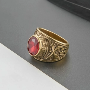 Macro shot of vintage gold military ring with a large faceted red gemstone and relief detail