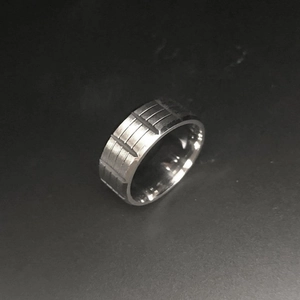 Detailed macro view of silver stainless steel ring with industrial horizontal grooved texture